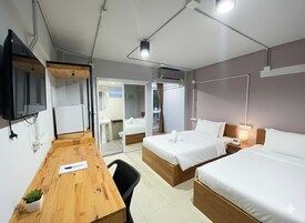 Habitación de hotel con dos camas, un escritorio, una silla, un televisor y aire acondicionado.