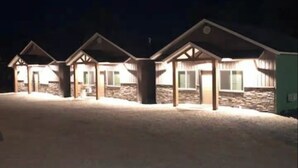 A row of motel-style buildings with a flat roof and a single-story structure, illuminated by exterior lighting. - On The Banks Of The Salmon River 2bed/ 2bath/ Sleeps 6 (Salmon)