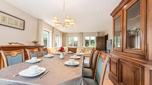 Comedor con una mesa grande dispuesta para una comida, rodeada de sillas con asientos acolchados.