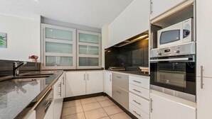 Una cocina moderna con armarios blancos, una encimera negra y un horno empotrado.
