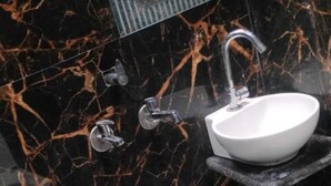 Een badkamer met een zwart marmeren wastafel, een spiegel en een douche.