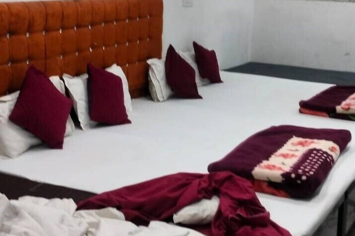 Une chambre d’hôtel avec un grand lit, plusieurs oreillers, une tête de lit et un ventilateur de plafond.