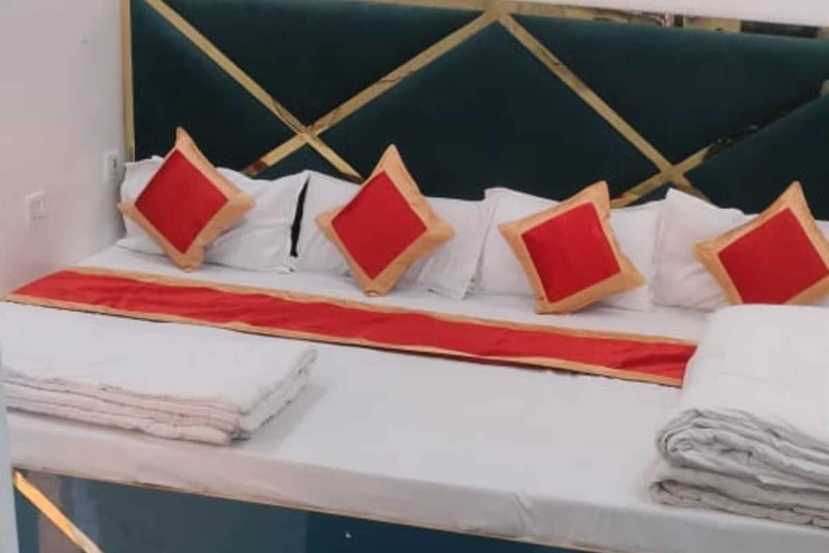 Une chambre d’hôtel avec un lit, une petite table, un banc et un pouf vert.