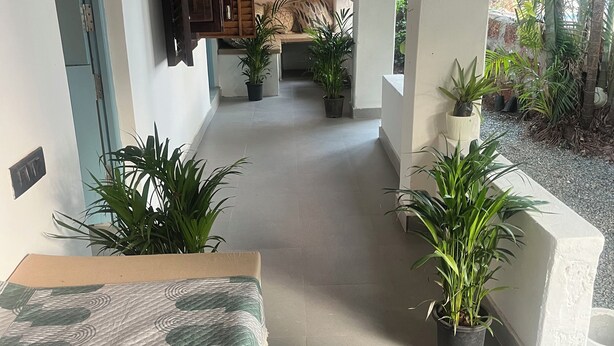 A covered outdoor seating area with a bench, potted plants, and a hanging fan. - Seaside Sanctuary (Canacona)