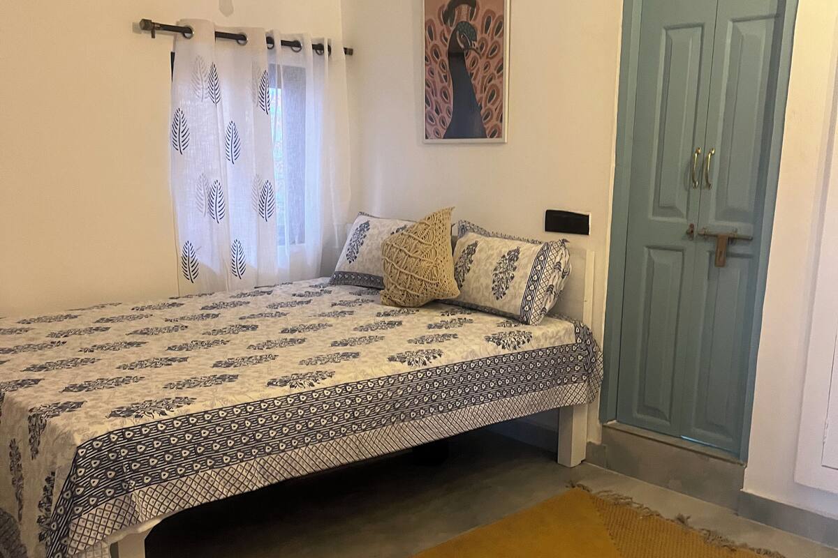 Una camera da letto con un letto, una ventola a soffitto, una porta e una finestra con tende.
