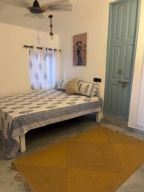 A bedroom with a bed, a ceiling fan, a door, and a window with curtains. - Seaside Sanctuary (Canacona)