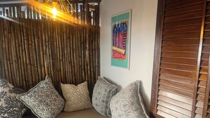 A cozy seating area with patterned cushions, a bamboo wall, and a poster. - Seaside Sanctuary (Canacona)