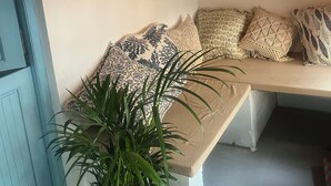 A cozy seating area with patterned cushions, a wall-mounted fan, and a hanging light fixture. - Seaside Sanctuary (Canacona)
