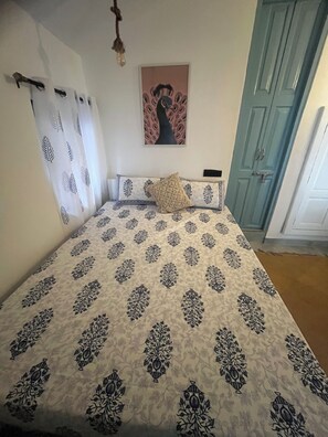 A bedroom with a bed, a wall-mounted picture, a door, and a curtain. - Seaside Sanctuary (Canacona)
