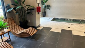 Een modern interieur met een houten bankje, plantenbakken en een betegelde vloer.