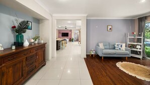 Un salón amplio con un mueble de madera, un sofá azul claro y un comedor al fondo.