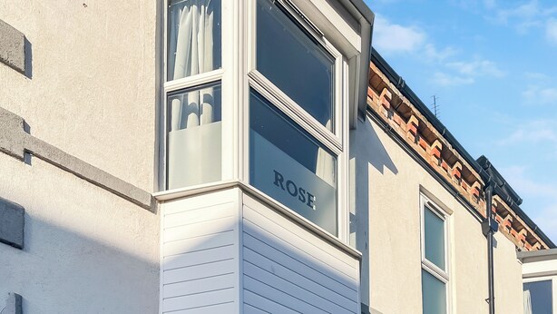 A corner of a building with a window labeled 'ROSE' and a white siding exterior. - A great apartment so close to the beach and harbour and within the town centre. (Bridlington)