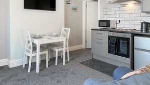 Una cucina moderna con zona pranzo, TV a schermo piatto, microonde, forno e macchina del caffè.