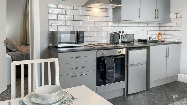 Una cucina moderna con forno a microonde, tostapane, bollitore e forno. C'è un tavolo da pranzo con piatti e posate.