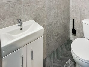 Ein Badezimmer mit einem weißen Waschbecken, einer Toilette und einem Boden mit Fischgrätmuster.