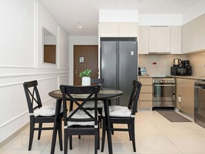 Eine moderne Küche mit Edelstahlgeräten, eine Essecke mit rundem Tisch und Stühlen sowie ein kleiner Blumentopf.
