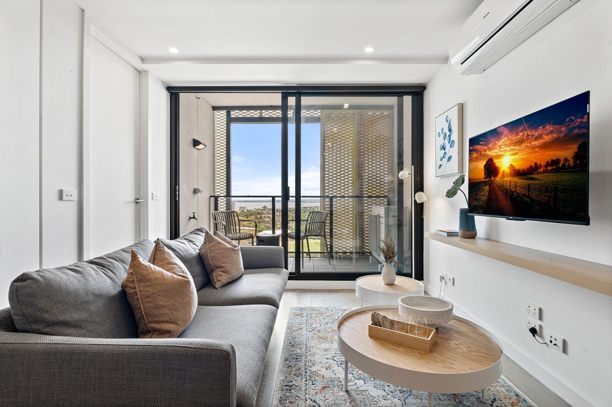A modern living room with a sofa, a coffee table, and a TV on the wall.