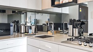 A modern kitchen with stainless steel appliances, a built-in oven, and a coffee machine. - Renovated 2-Bed Apartment with Balcony (St Kilda)