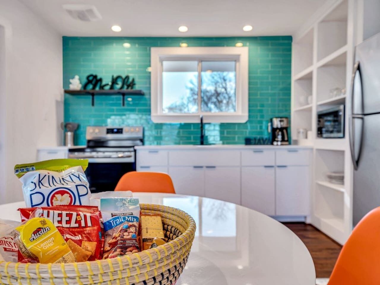 Een moderne keuken met een blauwgroene achterwand, witte kasten en een raam.