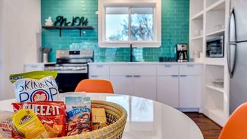 Een moderne keuken met een blauwgroene achterwand, witte kasten en een raam.