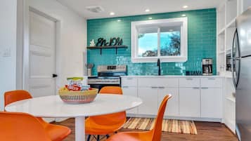Een moderne keuken met een blauwgroene achterwand, witte kastjes en een raam met uitzicht op de omgeving.