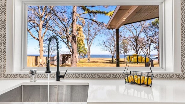 A kitchen with a view of a beach and trees. - Lago Vista- Waterfront | Kayaks | Views! (Wills Point)
