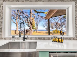 A kitchen with a view of a beach and trees.