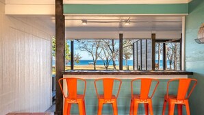 A bar area with four orange chairs and a counter, overlooking a beach. - Lago Vista- Waterfront | Kayaks | Views! (Wills Point)