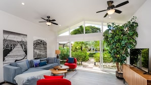 Ein modernes Wohnzimmer mit einem grauen Sofa, einem roten Sessel und einem Fernseher auf einem Holzschrank.