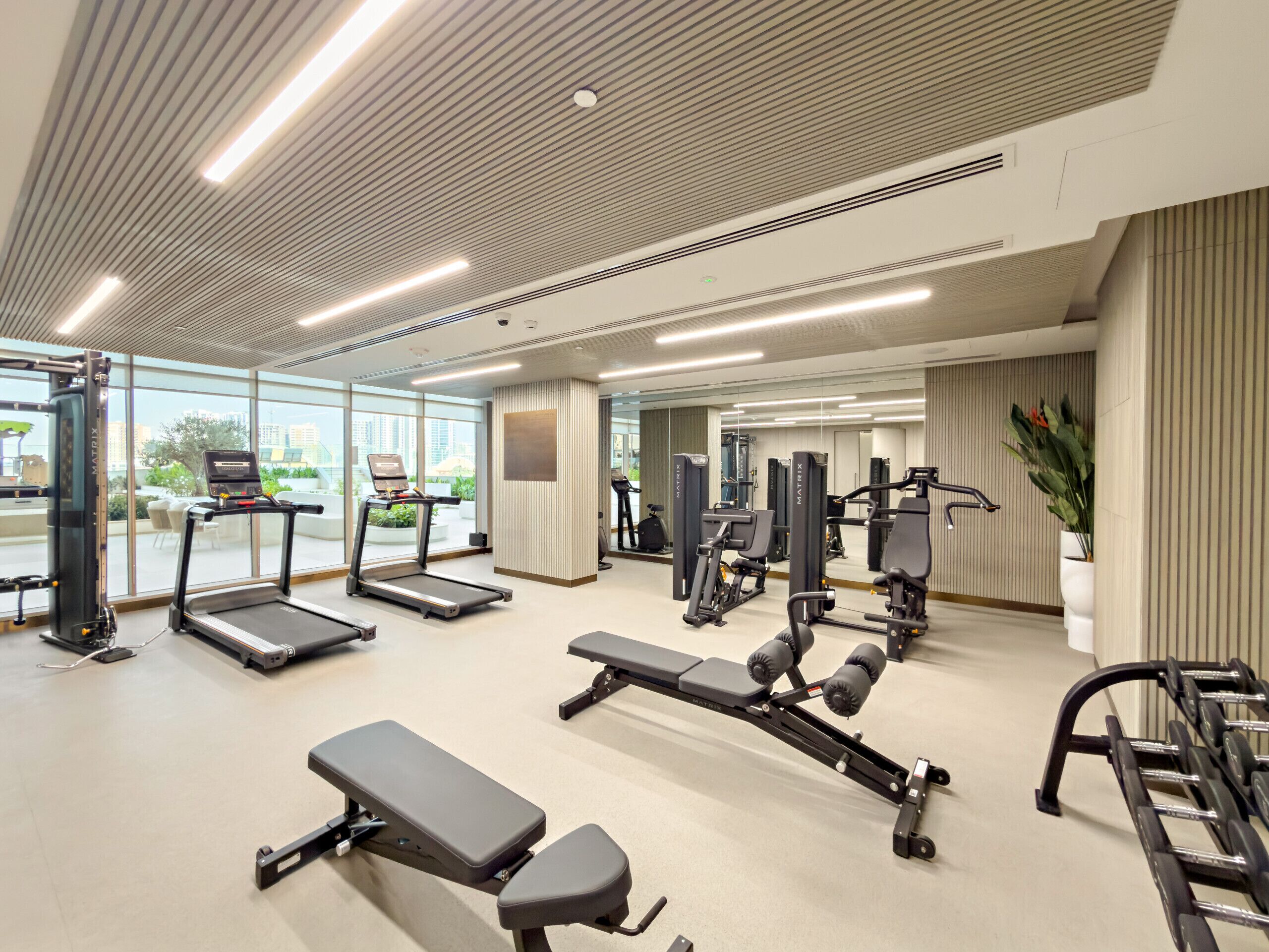 Una palestra moderna con tapis roulant, macchinari per pesi e panche.