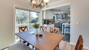 A dining area with a wooden table, chairs, and a chandelier. There is a view of a kitchen and a balcony with a railing. - 4 Seasons of Fun! Walhalla Home w/ Spacious Yard! (Walhalla)