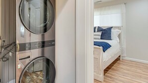 A compact room with a bed, a washing machine, and a mirror. - 4 Seasons of Fun! Walhalla Home w/ Spacious Yard! (Walhalla)