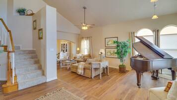 A spacious living room with a grand piano, a staircase, and a cozy seating area.