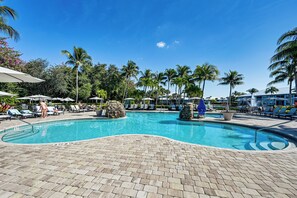 A pool area with lounge chairs and umbrellas, surrounded by palm trees and a clear blue sky. - “Overlooking 10th Fairway – 2 Free Rounds of Golf” (Naples)