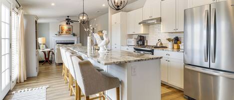 A modern kitchen with a central island, stainless steel appliances, and a chandelier.