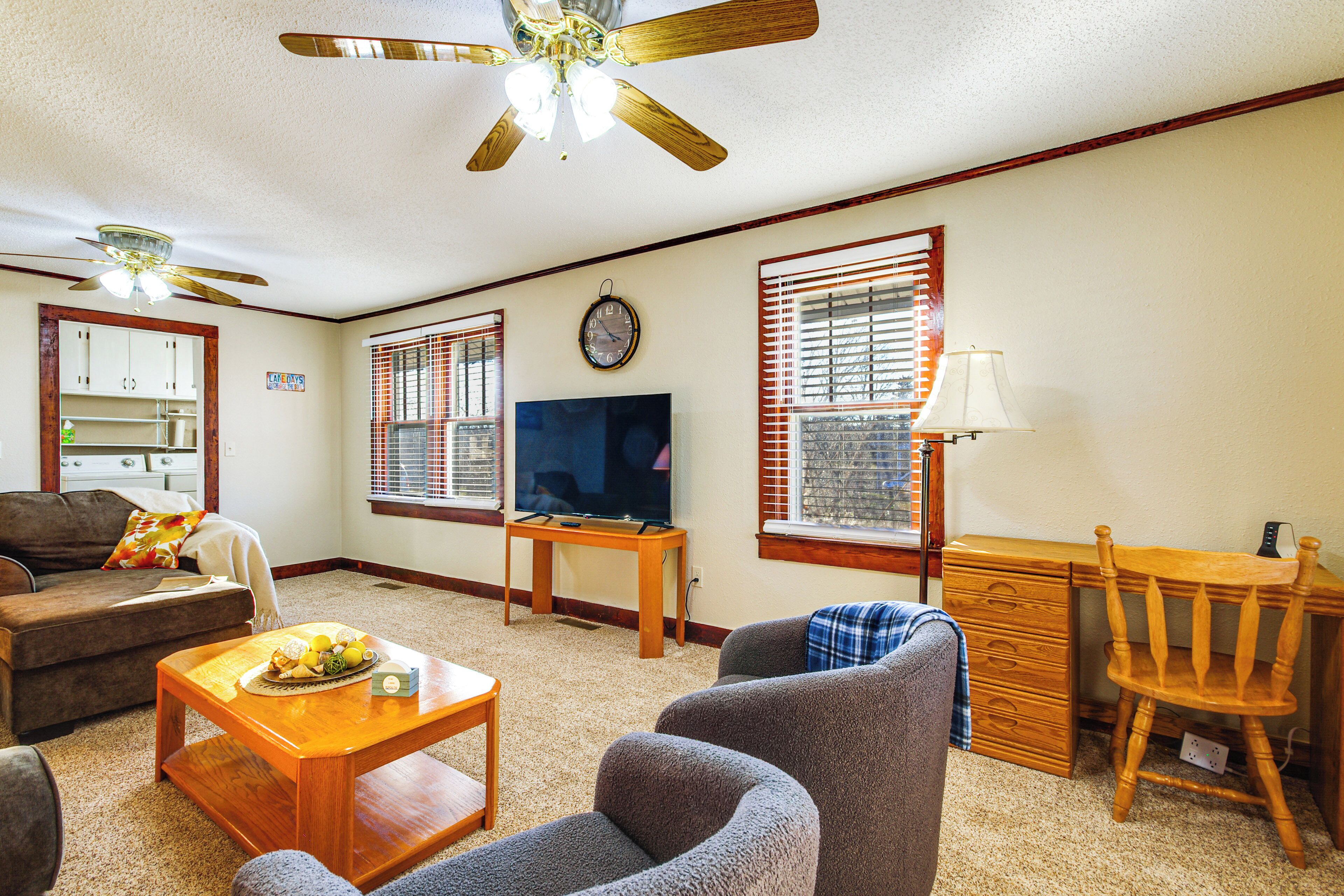 A living room with a ceiling fan, a TV, a wooden desk, and a couch.