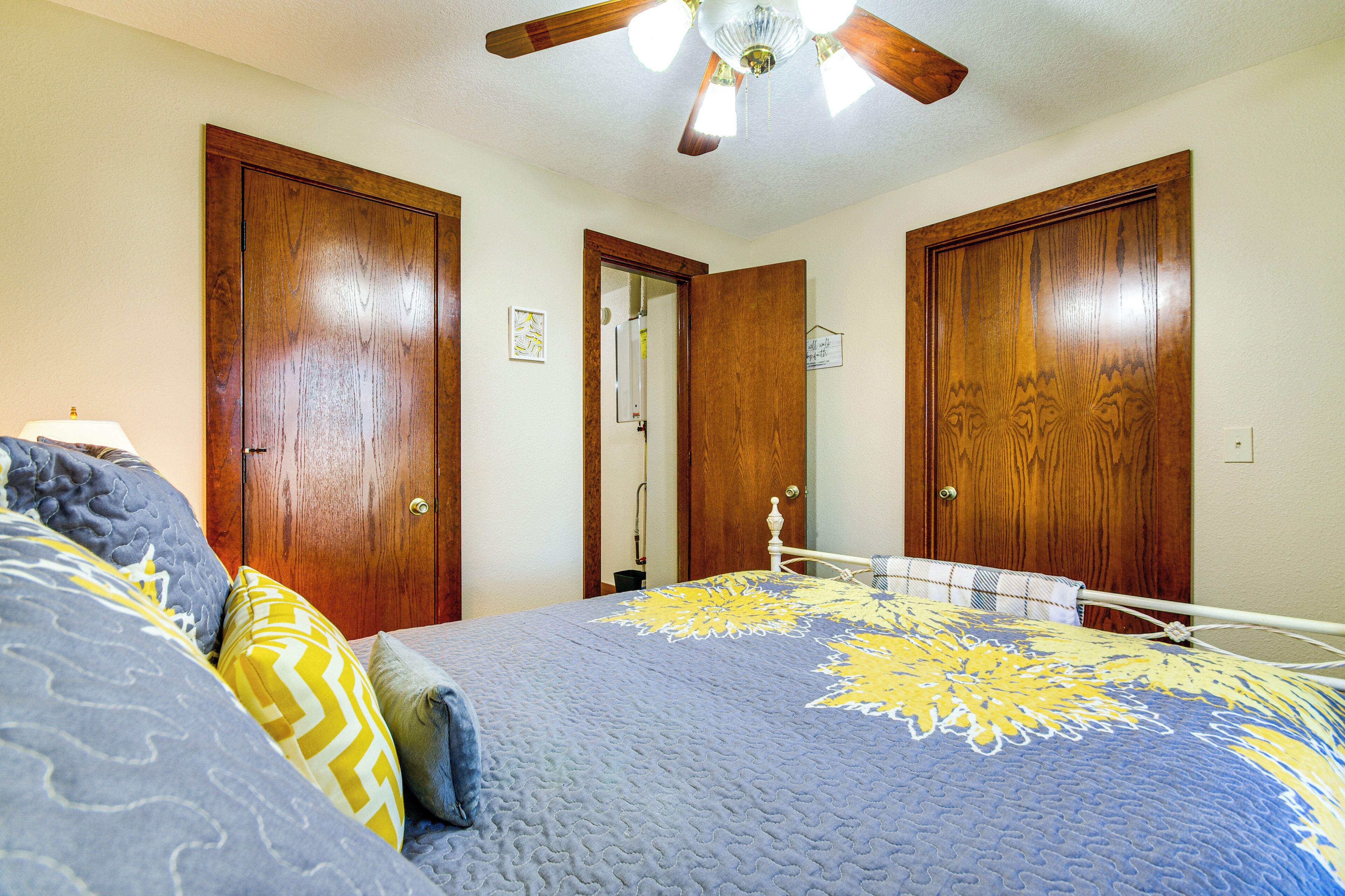 A bedroom with a bed, wooden doors, a ceiling fan, and a nightstand.