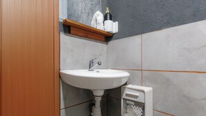 Une salle de bain avec un lavabo blanc, un distributeur de serviettes et un boîte de mouchoirs.