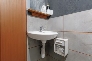 Ein Badezimmer mit einem weißen Waschbecken, einem Handtuchspender und einer Taschentuchbox.
