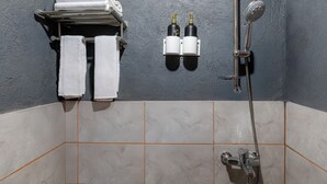 Kylpyhuone, jossa on suihku, kaksi pulloa shampoota ja pyyheteline, jossa on kaksi pyyhettä.