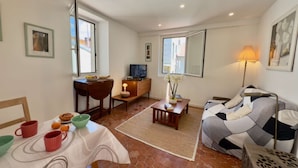Un salon confortable avec un canapé, une table à manger et des chaises, un téléviseur et une lampe.
