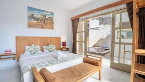 Une chambre spacieuse avec un grand lit, un banc en bois, un tableau représentant une jetée et une vue sur un balcon avec un escalier.