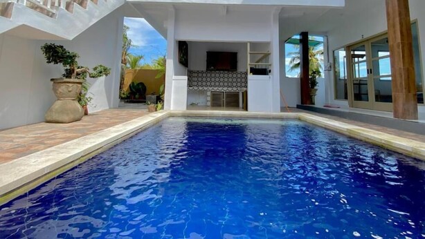 Une maison moderne dotée d’une piscine, d’un patio couvert et offrant une vue sur le ciel.