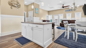 A modern kitchen with white cabinets, a granite countertop, and a dining area with a table and chairs. - Isle Always Luv View-New To Rental Market, 5beds/Pet Friendly/Ocean Views (ocean isle beach)