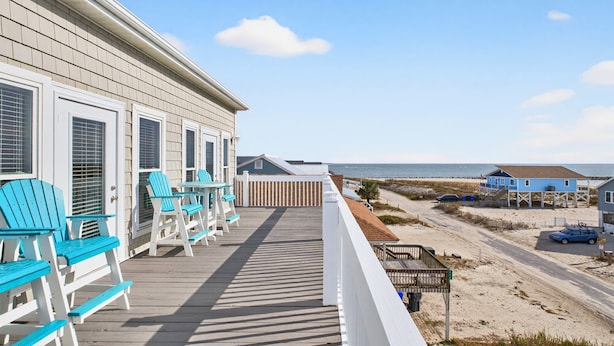 A wooden deck with blue Adirondack chairs, a white railing, and a view of the beach and ocean. - Isle Always Luv View-New To Rental Market, 5beds/Pet Friendly/Ocean Views (ocean isle beach)