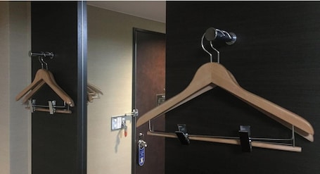Two wooden hangers on a wall, one with a metal clip and one with a hook.