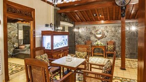 A cozy room with wooden furniture, a stone wall, and a television. - Ndalem Kartowikoro 1835 (Surakarta)