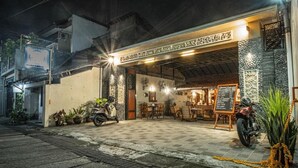A restaurant with outdoor seating, a motorcycle parked outside, and a signboard with the restaurant's name. - Ndalem Kartowikoro 1835 (Surakarta)