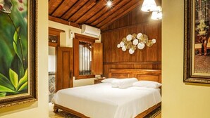 A bedroom with a wooden bed, a headboard with a decorative panel, and a large mirror. - Ndalem Kartowikoro 1835 (Surakarta)