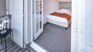 A bedroom with a bed, a chair, and a door leading to another room.